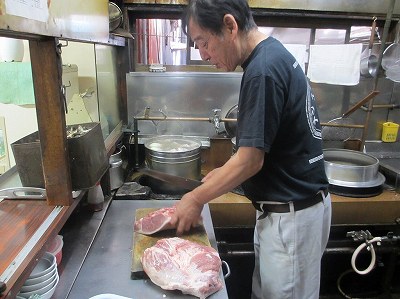 肉をカットする坂田店主